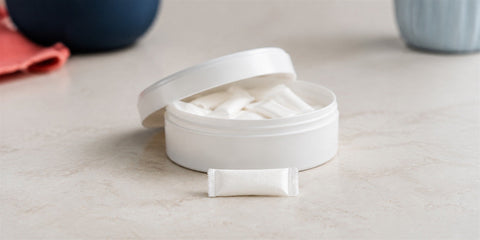 Open nicotine pouch can with a single white pouch in front