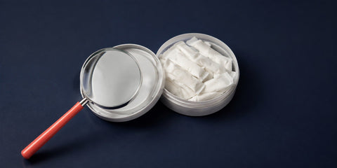 Magnifying glass over an open nicotine pouch can
