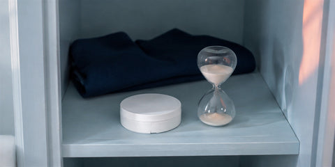 Closed nicotine pouch can beside an hourglass