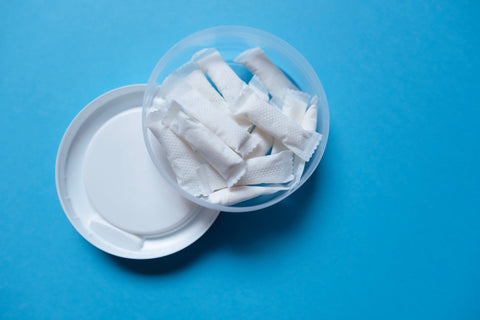Open can of white nicotine pouches on a blue background