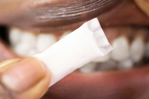 Adult placing a white nicotine pouch under the upper lip