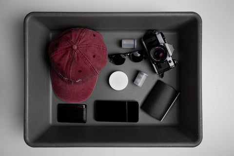 Tray with a white nicotine pouch can, cap, camera and phone