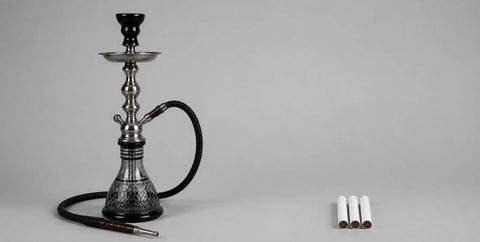 Shisha water pipe beside three unlit cigarettes on a grey background